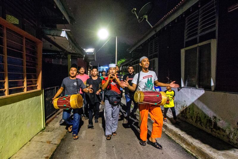 A group of young people sing and play traditional music as they walk around a village to announce Suhoor, the pre-dawn meal, during Ramadan in Kampung Bukit Piatu, Malacca, Malaysia.  EPA