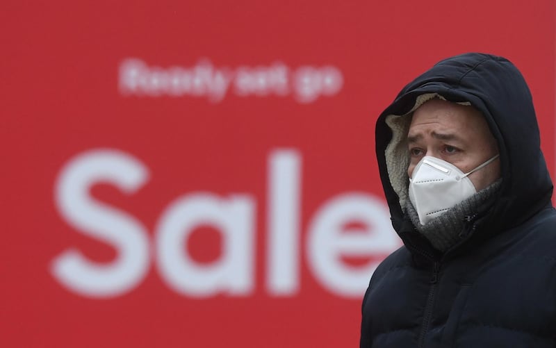 A masked man passes a Sale sign on Oxford Street in London. EPA