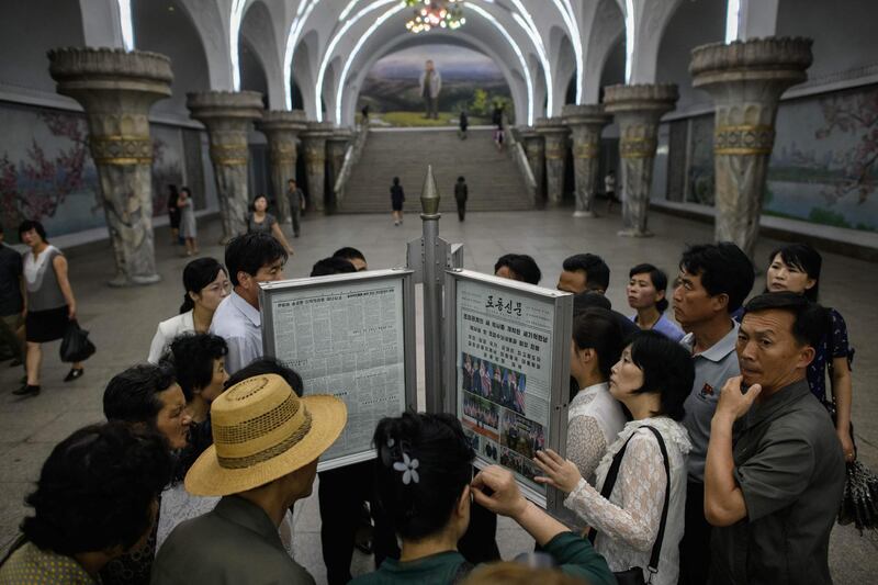 Commuters gather round the latest copy of the Rodong Sinmun newspaper showing images of North Korean leader Kim Jong Un meeting with US president Donald Trump during their summit in Singapore, at a news stand on a subway platform of the Pyongyang metro. Ed Jones / AFP