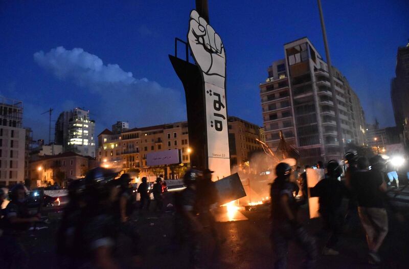 Members of the Lebanese security forces intervene after the ‘Revolution fist’, symbol of Lebanon’s October 2019 uprising, was set on fire during clashes between anti-government protesters and supporters of former prime minister Saad Hariri, in the capital Beirut's central Martyr's square. AFP