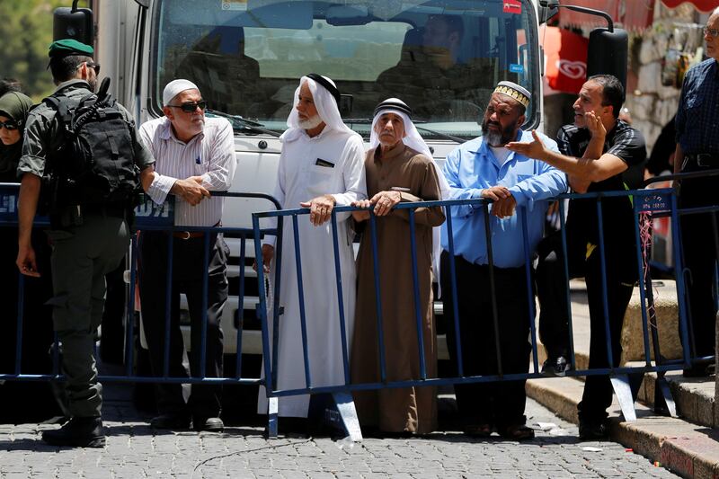 Palestinians stand next to a police barricade as they wait for the compound known to Muslims as Noble Sanctuary and to Jews as Temple Mount to be reopened, in Jerusalem's Old City July 16, 2017. REUTERS/Ammar Awad