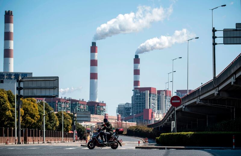 (FILES) This file photo taken on March 6, 2017 shows a man riding his scooter near the Shanghai Waigaoqiao Power Generator Company coal power plant in Shanghai. China must stop building new coal power plants and ramp up its wind and solar capacity if it wants to become carbon neutral by 2060, researchers said on November 20, 2020. - 
 / AFP / JOHANNES EISELE
