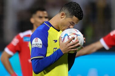 Nassr's Portuguese forward Cristiano Ronaldo kisses the ball before taking a penalty during the Saudi Pro League football match between Al-Wehda and Al-Nassr at the King Abdulaziz Stadium in Mecca on February 9, 2023.  (Photo by AFP)