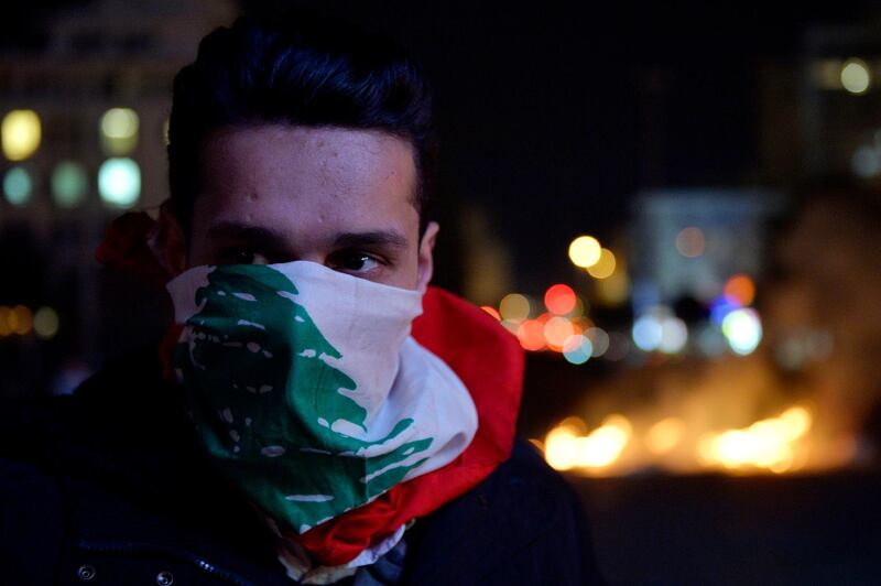 A protester covers his face with the Lebanese flag during ongoing protests at Ring Bridge in Beirut. EPA