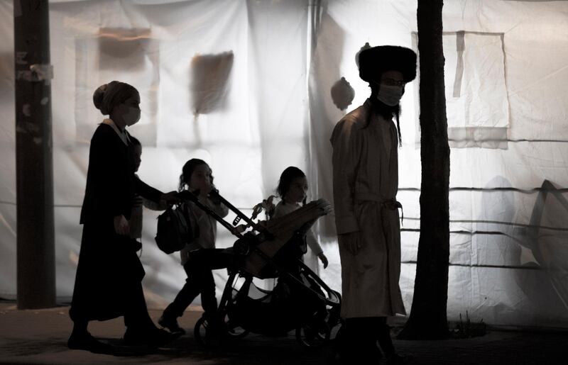 An ultra-Orthodox family passing next to sukkah (hut) during the Sukkot holiday, the Feast of the Tabernacles, in the ultra-Orthodox neighbourhood of Meah Shearim, Jerusalem, Israel, 07 October. Israel is under a full three-week lockdown aimed to prevent the spread of the coronavirus. Atef Safadi