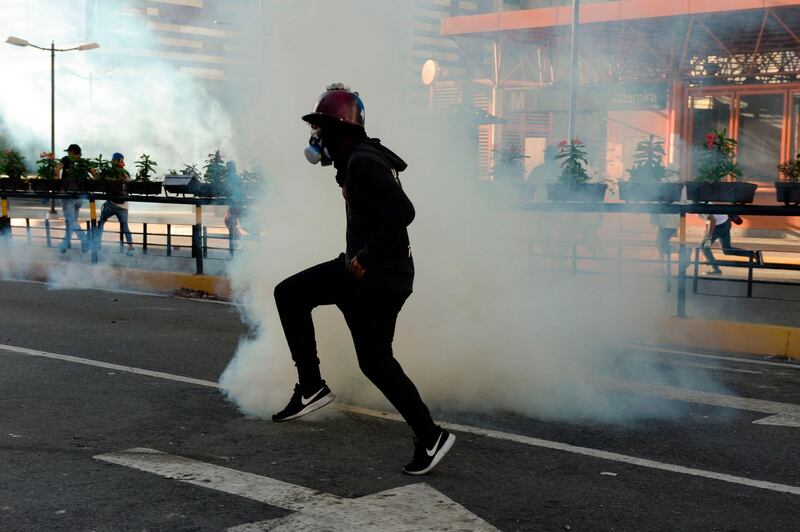 An opposition demonstrator wears a gas mask against tear gas during clashes with security forces in a protest against the government of President Nicolas Maduro on the anniversary of the 1958 uprising that overthrew the military dictatorship, in Caracas on January 23, 2019.  Venezuela's National Assembly head Juan Guaido declared himself the country's "acting president" on Wednesday during a mass opposition rally against leader Nicolas Maduro. / AFP / Federico Parra                      

