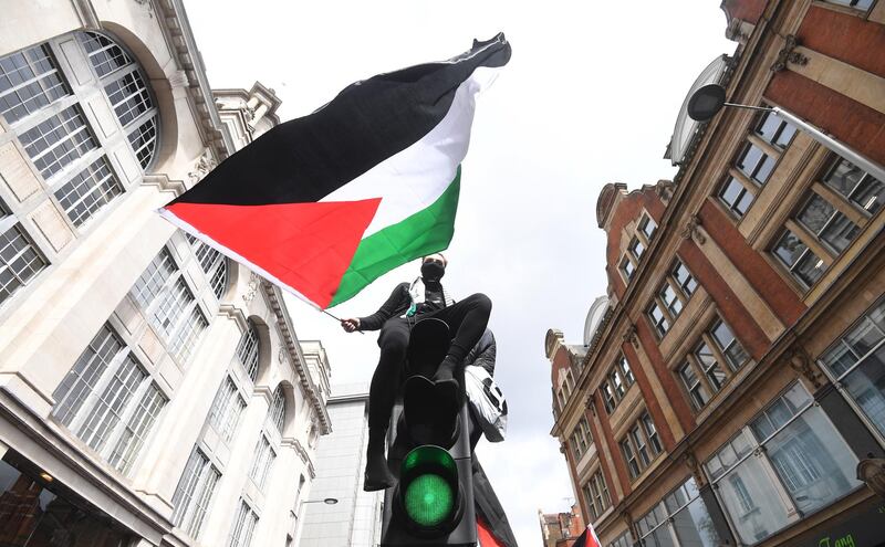 A supporters waves the Palestinian flag atop a traffic light pole during a demonstration outside the Israeli embassy in London, Britain. EPA
