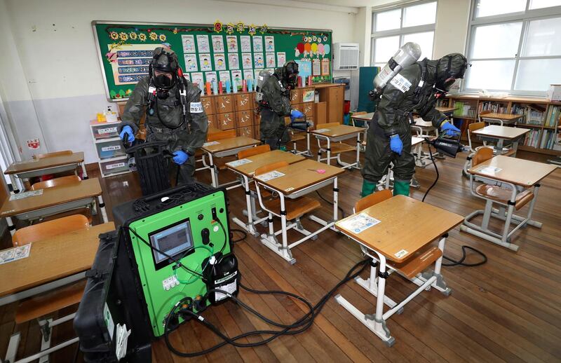 South Korean army soldiers spray disinfectant to help reduce the spread of the new coronavirus in a class at Cheondong elementary school in Daejeon, South Korea. Yonhap via AP
