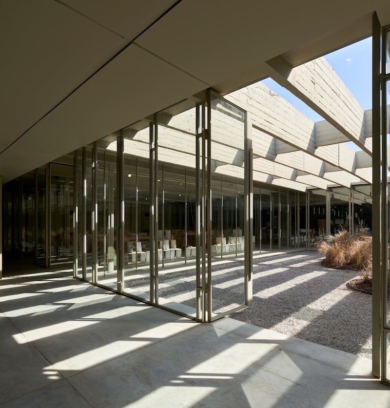 Defined by a series of lightweight steel and glass panels registering the ceiling's rhythmic structural grid, the new flexible partition seamlessly connects all functions to each other and to the central courtyard beyond.