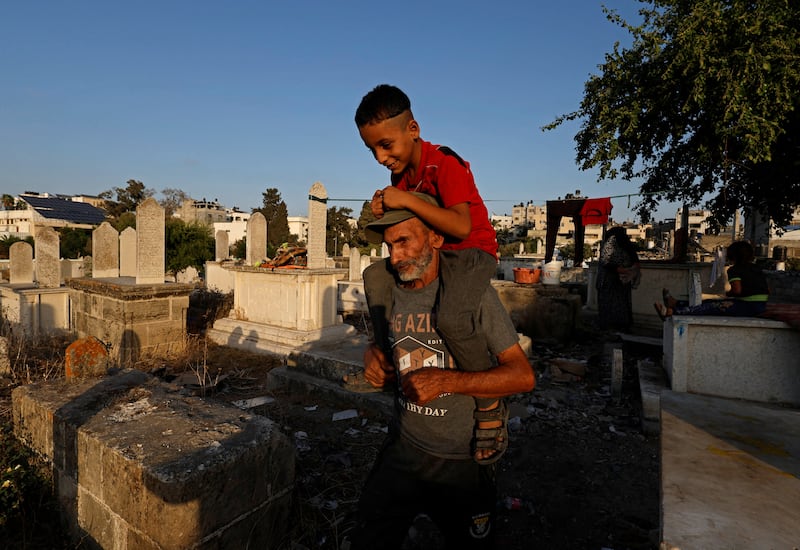 Omar Kuhail, 65, carries his grandson Mohammad, 7, on his shoulders in Sheikh Shaban cemetery, where they live. Gaza needs 14,000 new housing units a year, according to officials.
