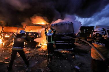 Members of the Syrian civil defence try to put out several trucks and freight vehicles on fire in the aftermath of air strikes at a depot near the Bab al-Hawa border crossing between Syria and Turkey in Syria's rebel-held northwestern Idlib province. AFP