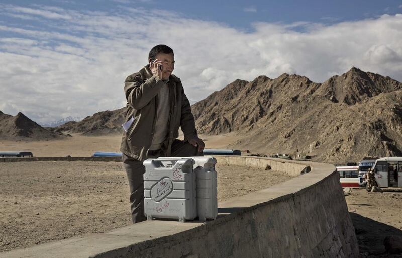 An election worker talks on the phone as he stands with voting machines while leaving a central collection point to head for a polling station.