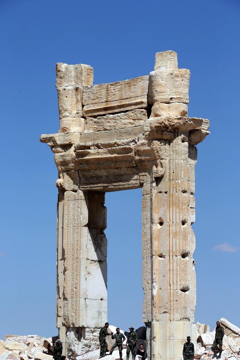 Syrian soldiers stand on March 31, 2016 on the ruins of Temple of Bel's "Cella", which was blown up by jihadists of the Islamic State (IS) group in August 2015, in the ancient Syrian city of Palmyra. - The main building of the ancient temple, the "Cella", was destroyed by jihadists of the Islamic State group in August 2015 as well as a row of columns in its immediate vicinity. Syrian troops backed by Russian forces recaptured Palmyra on March 27, 2016, after a fierce offensive to rescue the city from jihadists who view the UNESCO-listed site's magnificent ruins as idolatrous. (Photo by JOSEPH EID / AFP)