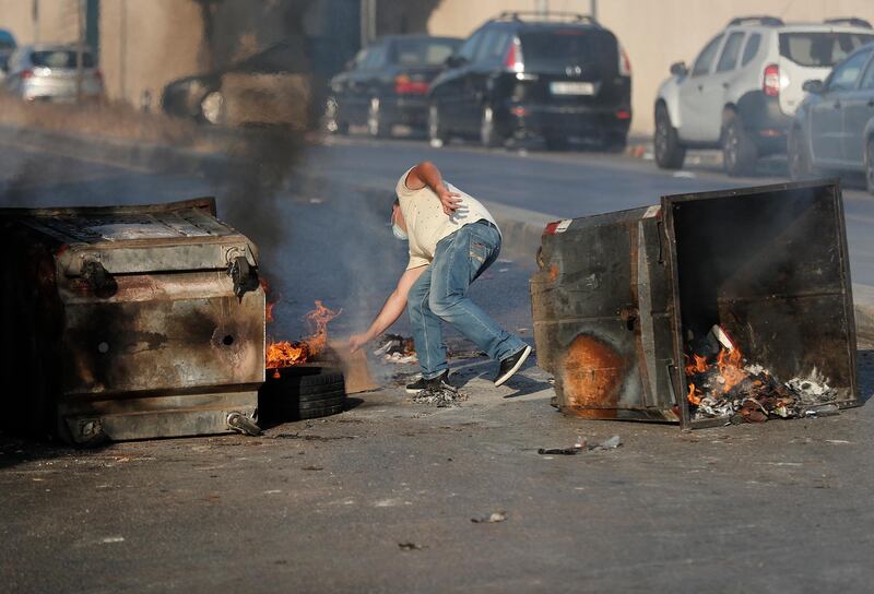 An anti-government protester burns tires and garbage containers to block roads, during a protest against the economic crisis, in Beirut, Lebanon. AP Photo