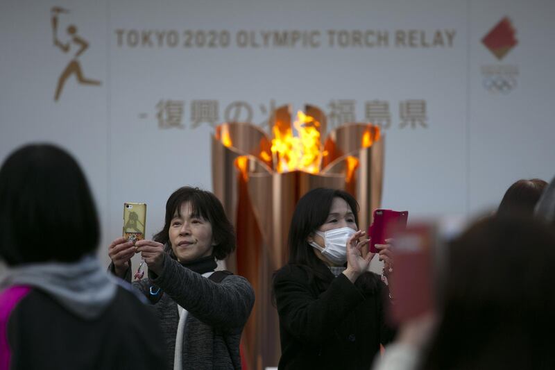People take pictures with the Olympic Flame during a ceremony in Fukushima City, Japan. AP