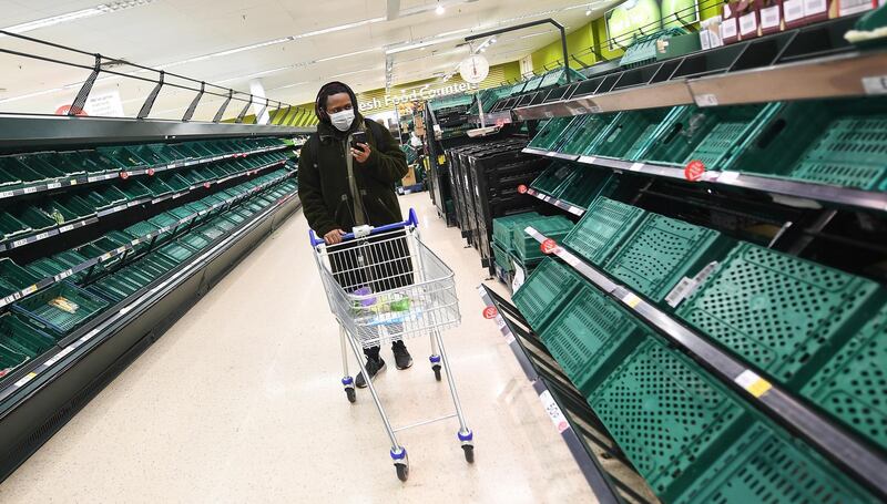 A shopper passes empty shelves at a Tesco supermarket in London. EPA