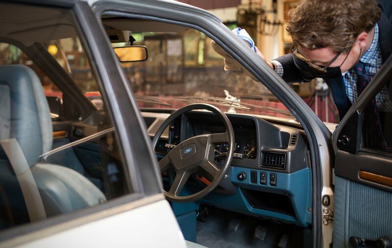 Auctioneer Lewis Rabett polishes the 1981 silver Ford Escort 1. 6L Ghia saloon car once owned by Princess Diana before it was auctioned. AP