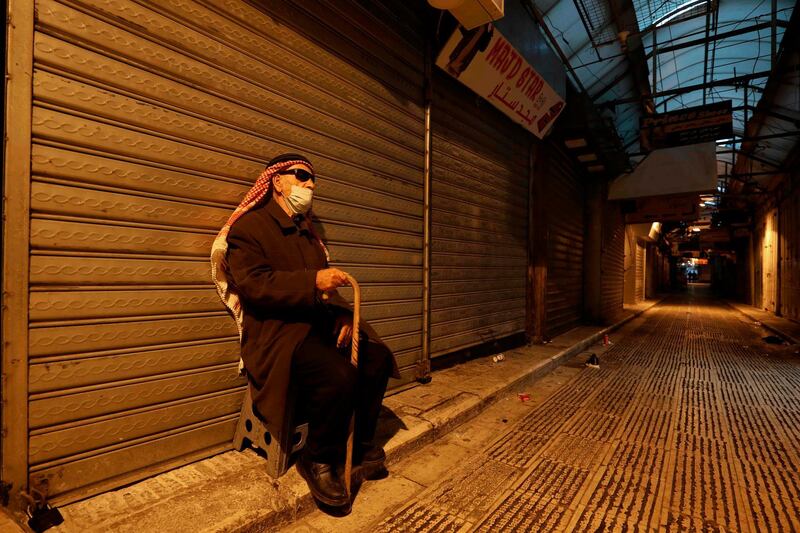 A Palestinian blind man sits by shuttered shops on an empty street in the West Bank city of Nablus. AFP