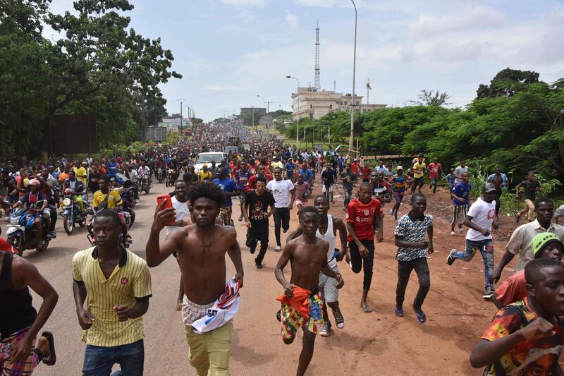 People celebrate in the streets with members of Guinea's armed forces after the arrest of Guinea's president, Alpha Conde, in a coup d'etat in Conakry.  - Guinean special forces seized power in a coup on September 5, arresting the president and imposing an indefinite curfew in the poor west African country.  AFP