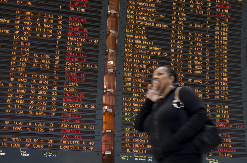 A traveller at the Charles de Gaulle international airport’s terminal 2 walks in front of a flight information board during a strike by air traffic controllers. EPA
