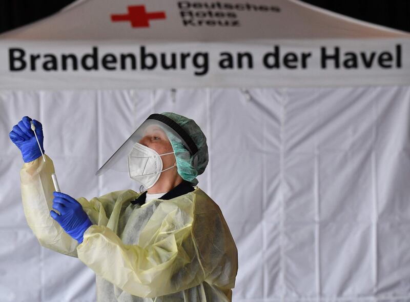 A member of the Deutsches Rotes Kreuz DRK explains a testing kit at the KVBB (Kassenaerztliche Vereinigung Berlin Brandenburg) Corona testing station inside the Metropolis at the film park Babelsberg in Potsdam, Eastern Germany, on November 16, 2020. / AFP / Tobias Schwarz
