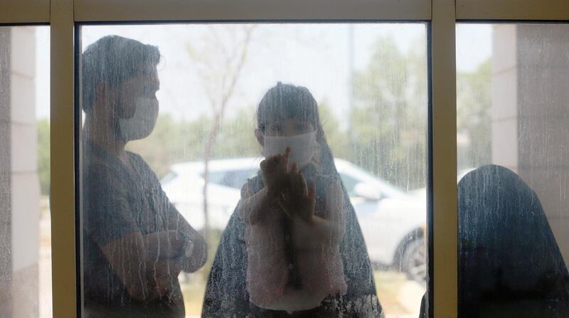 A child who suffers from cancer looks through the window with her family at the Children's Hospital for Cancer Diseases, amid the spread of the coronavirus, in Basra, Iraq. Reuters