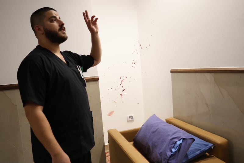 A hospital worker shows reporters the bed on which one of the men was shot to death. EPA