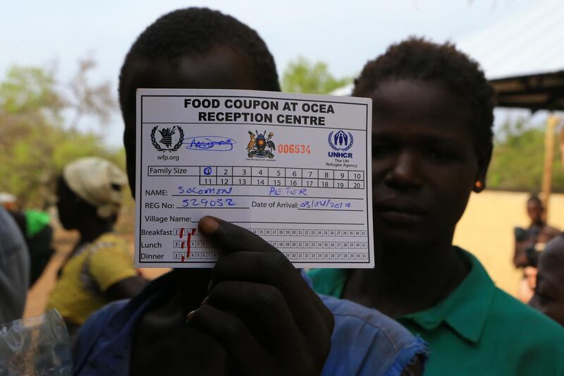 South Sudanese refugee displaced by fighting uses his meal card to cover his face as he waits to be served porridge on arrive at Imvepi settlement in Arua district, northern Uganda, April 4, 2017. Picture taken April 4, 2017. REUTERS/James Akena