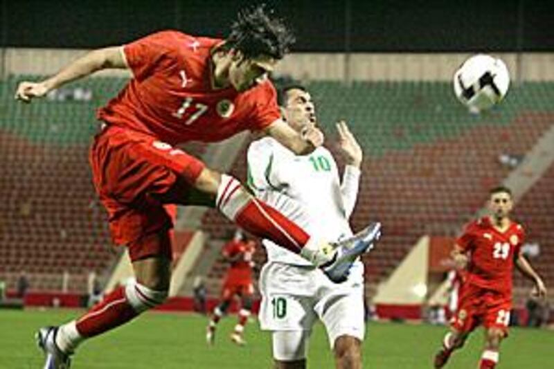 Hussein Ali Baba of Bahrain, left, clears the ball spectacularly as Iraq's Yunes Mahmud tries to get out of the way.