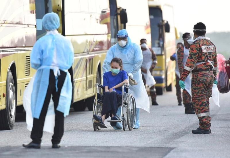 A Malaysian national being directed onto a bus by health officials in protective suits as she arrived at the Kuala Lumpur International Airport in Sepang, Malaysia, after being evacuated from China's Wuhan.  AP