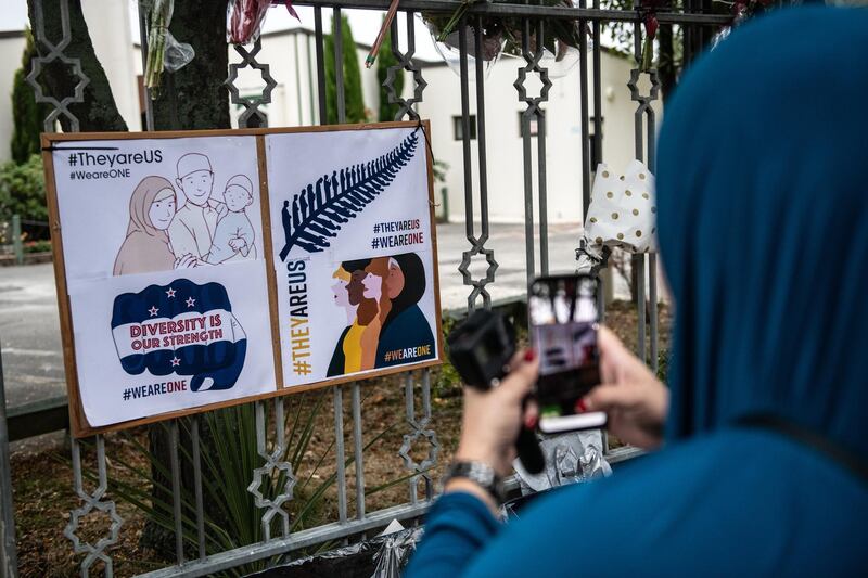 A Muslim woman photographs a poster hung on the fence of Al Noor mosque after it was officially reopened following last week's attack. Getty Images