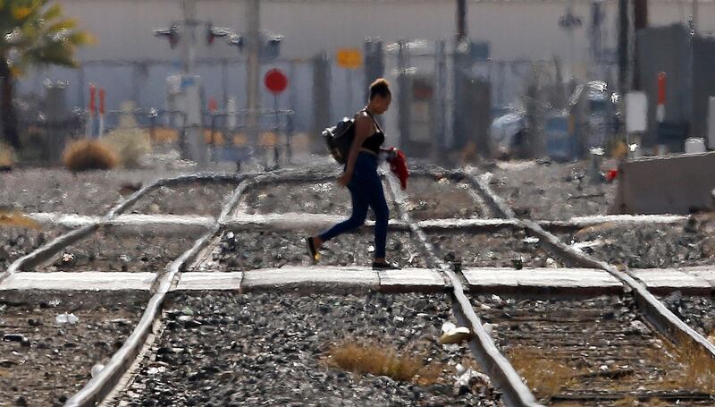 While the heat waves rise up from the ground, a woman crosses the railroad tracks as temperatures climb past 112-degrees Thursday, July 5, 2018, in Phoenix. (AP Photo/Ross D. Franklin)