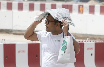 DUBAI , UNITED ARAB EMIRATES , JULY 14 – 2017 :- One of the pedestrian covering himself with the newspaper in the hot and dusty weather in International City area in Dubai. ( Pawan Singh / The National ) 