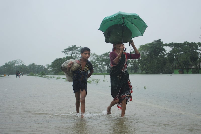 People wade along a road in a flooded area following heavy monsoon rainfalls on the outskirts of Sylhet on June 17, 2022.  - Bangladesh has deployed troops to help two million people stranded by floods after relentless monsoon rains inundated huge swathes of territory for the second time in weeks, officials said on June 17.  (Photo by AFP)