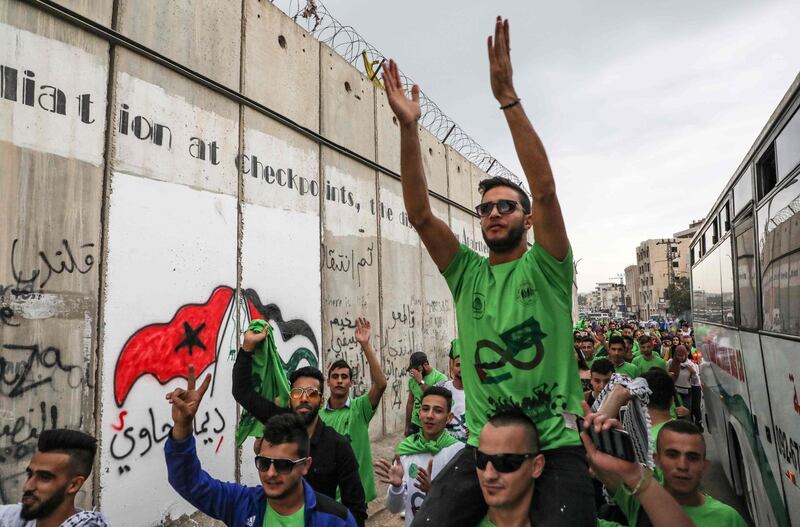 Palestinian football fans carry the Saudi flag ahead of today's match between their national football team and that of Saudi Arabia for a WC2020 qualifying match, in the Israeli occupied West Bank town of al-Ram. On the left is a section of the Israel's controversial seperation barrier. The game would mark a change in policy for Saudi Arabia, which has previously played matches against Palestine in third countries. Arab clubs and national teams have historically refused to play in the West Bank, where the Palestinian national team plays, as it required them to apply for Israeli entry permits.  AFP
