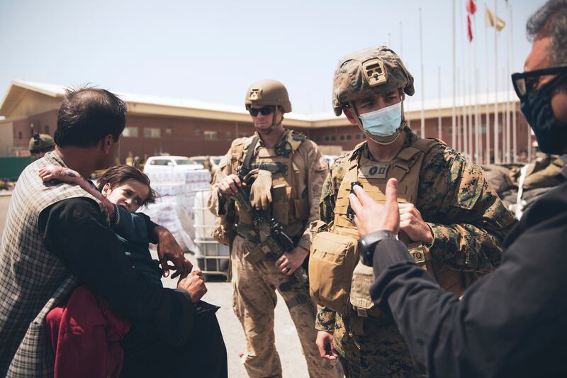 A US  Navy medical surgeon talks to an interpreter as he provides medical assistance to a family during an evacuation at Hamid Karzai International Airport in Kabul. AP Photo