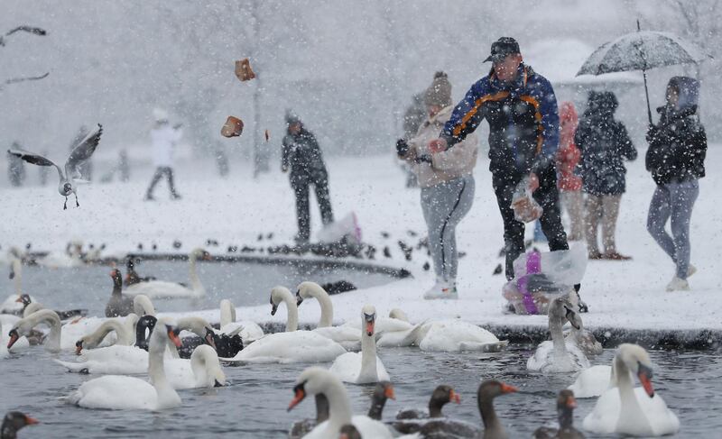 A man feeds the birds at the Round Pond in Kensington Gardens as snow falls in London. AP Photo