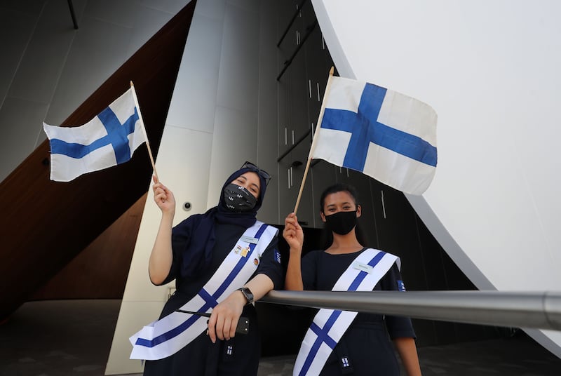 Staff wave flags outside the Finland pavilion.