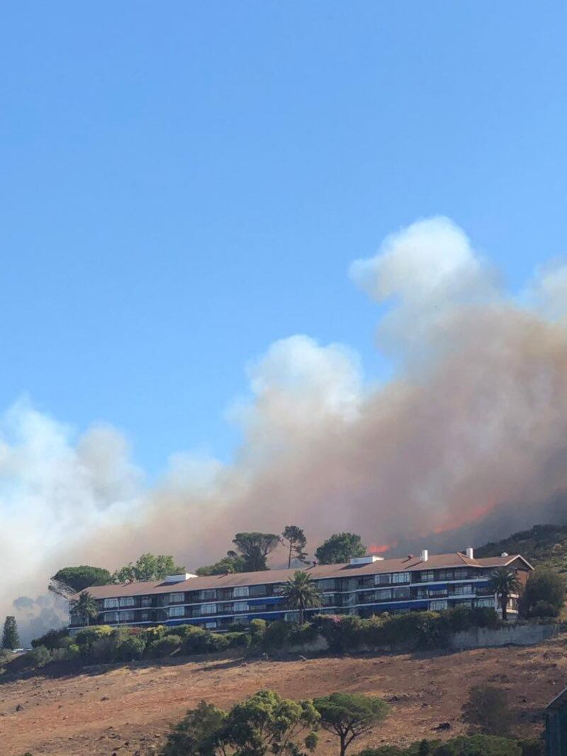 Smoke rises from a burning mountainside behind a building in Cape Town. Chantal Louw / via Reuters