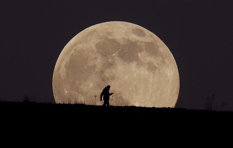 A man walks over Ivinghoe Beacon as the Wolf Moon rises, in Ivinghoe, Britain, January 17, 2022.  REUTERS / Matthew Childs