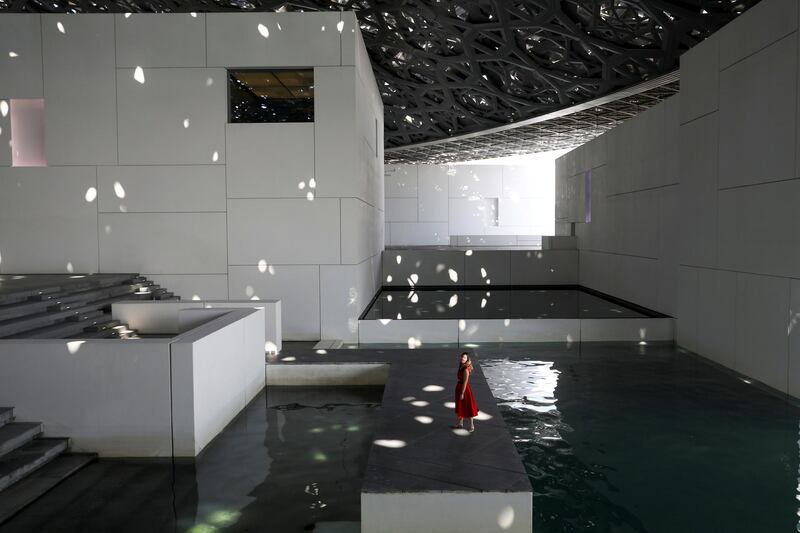 A visitor walks through a patch of light at Louvre Abu Dhabi. The museum's iconic done, designed by Jean Nouvel, filters natural light to produce this dappled effect. Christopher Pike  / REUTERS