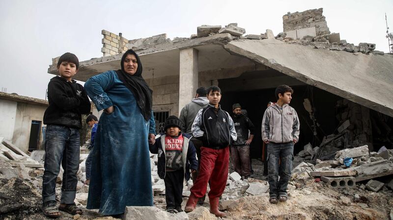 Syrians stand in a street next to debris and rubble from buildings which were damaged by reported air strikes in the rebel-held town of Orum al-Kubra, in the northern Syrian province of Aleppo. AFP