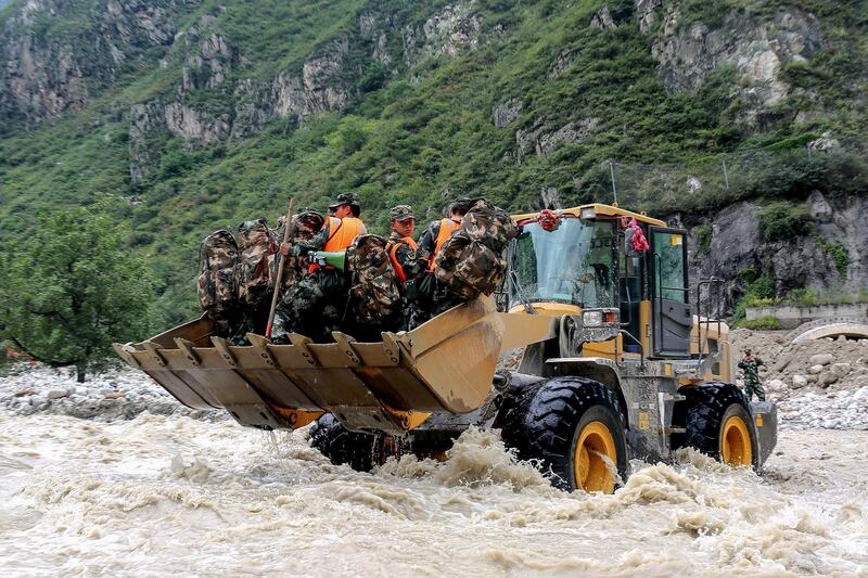 This photo taken shows a bulldozer carrying Chinese paramilitary police officers as they head  to a site of a mudslide caused by heavy rainfall in Wenchuan county, in China's southwestern Sichuan province.  AFP
