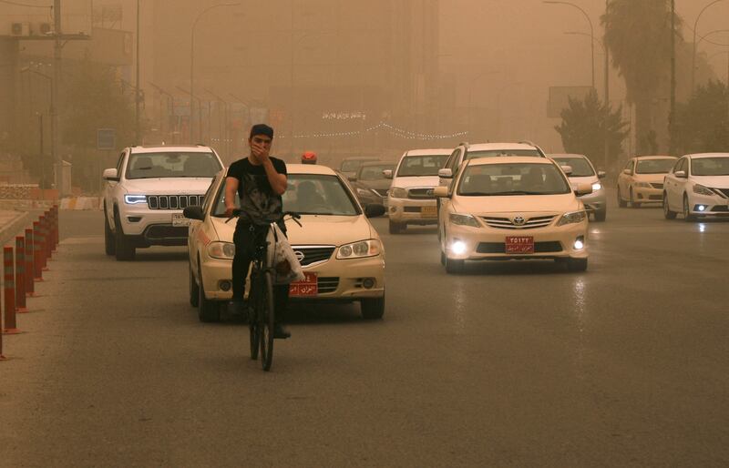 In Arbil a cyclist uses his hand during the sandstorm when a facemask would have been a better option.