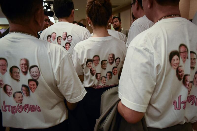 Members of the Phure Chart Thai Club wear T-shirts emblazoned with faces of political rivals, including Thailand's current Prime Minister Prayuth Chan-O-Cha  (C) and former prime ministers Thaksin Shinawatra (top R) and Yingluck Shinawatra (top L), at the Office of the Election Commission of Thailand in Bangkok on March 2, 2018.
More than 30 new Thai political parties submitted names and logos on the opening day of party registration in Bangkok on March 2, an early step in the junta-ruled kingdom's halting return to democracy. / AFP PHOTO / Lillian SUWANRUMPHA