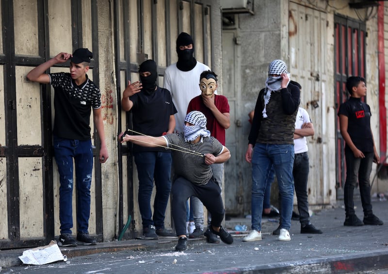 Palestinians throw stones at Israeli forces during protests over Jerusalem's annual flag march, in the West Bank city of Hebron. EPA