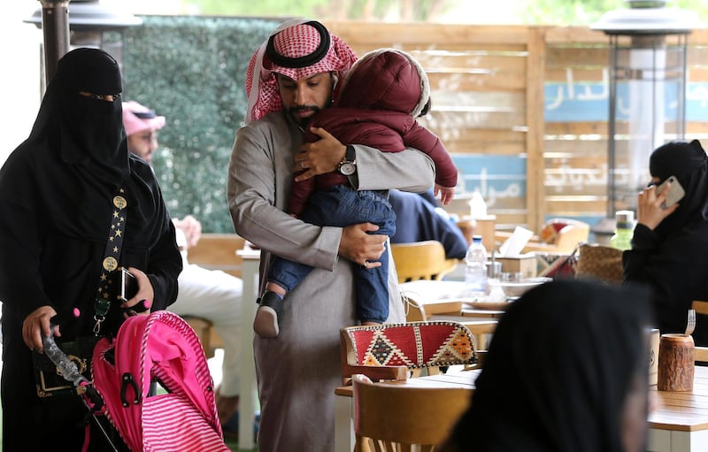 A Saudi man carries his son as they sit a at cafe in Riyadh. Reuters