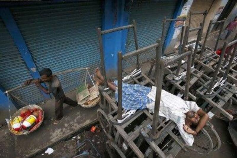 An Indian man sleeps on a handcart in front of closed shops during a nationwide strike in Gauhati over a government decision to open the country’s huge retail market to foreign companies and to cut fuel subsidies.