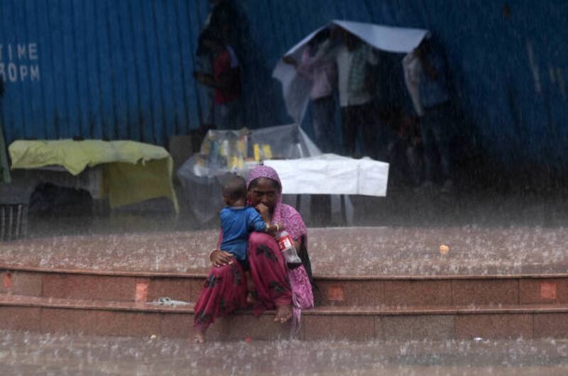 NEW DELHI, INDIA - AUGUST 2: An homeless with her child sit under heavy rain at Rajiv Chowk on August 2, 2021 in New Delhi, India. Rains continued to lash parts of Delhi NCR , extensive waterlogging and traffic snarls were reported at several places in the city  (Photo by Mohd Zakir / Hindustan Times via Getty Images)