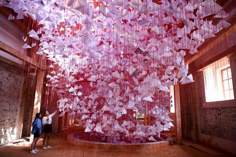 Visitors look at an installation called 'Tell me your Story' by Japanese artist Chiharu Shiota at the 14th edition of the European Nomadic biennale held in Kosovo. AFP